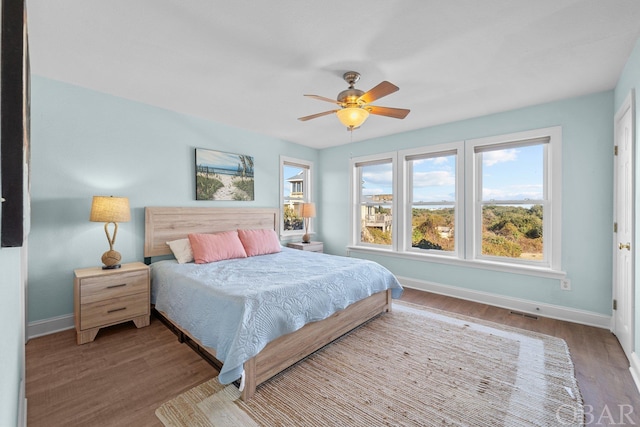 bedroom with ceiling fan, wood finished floors, and baseboards