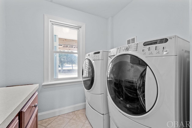 washroom featuring cabinet space, light tile patterned floors, baseboards, and washing machine and clothes dryer