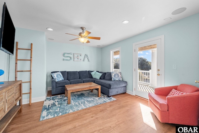 living room with a ceiling fan, light wood-style flooring, and baseboards