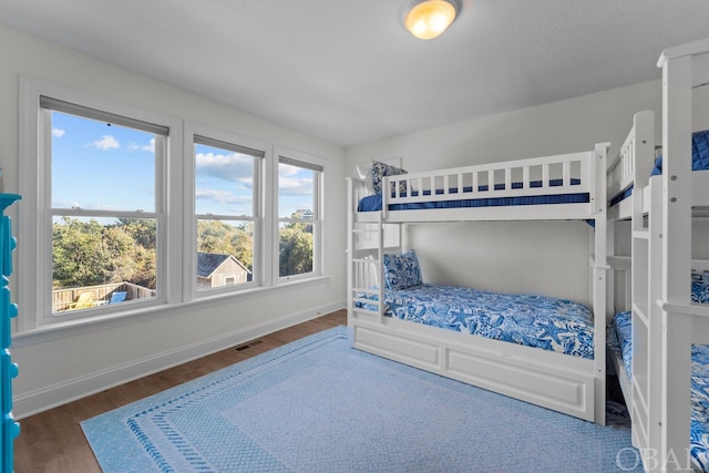 bedroom with dark wood finished floors, visible vents, and baseboards