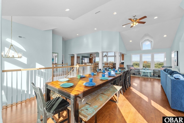 dining room featuring visible vents, high vaulted ceiling, wood finished floors, and decorative columns