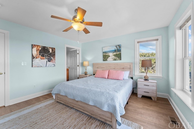 bedroom with baseboards, visible vents, a ceiling fan, and light wood-style floors