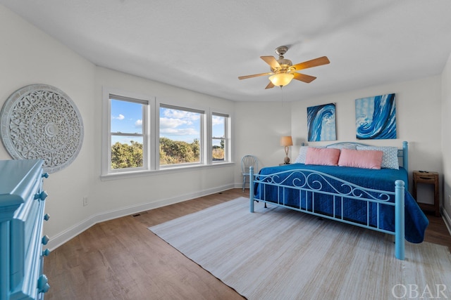 bedroom featuring a ceiling fan, baseboards, and wood finished floors