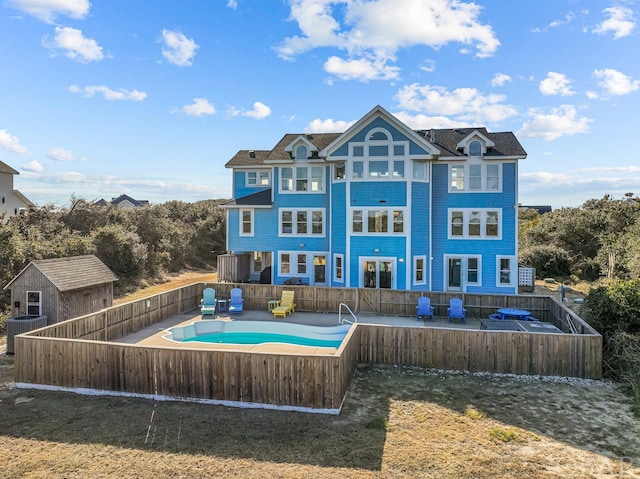 rear view of property featuring a fenced in pool, a fenced backyard, and central AC