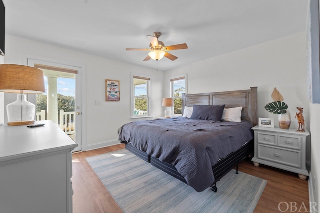 bedroom with dark wood-type flooring, access to outside, multiple windows, and ceiling fan