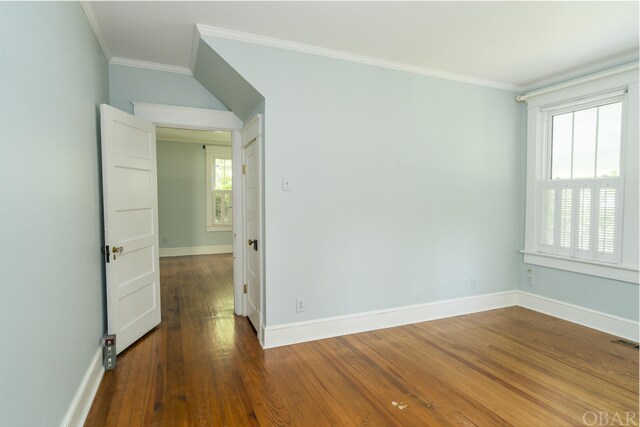 unfurnished room featuring baseboards, wood finished floors, visible vents, and crown molding