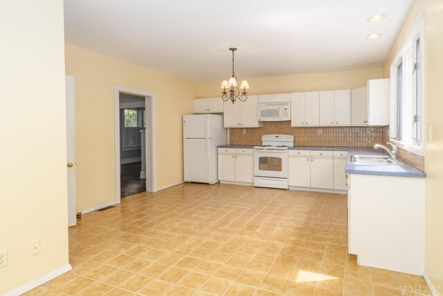 kitchen featuring a notable chandelier, hanging light fixtures, white cabinets, a sink, and white appliances