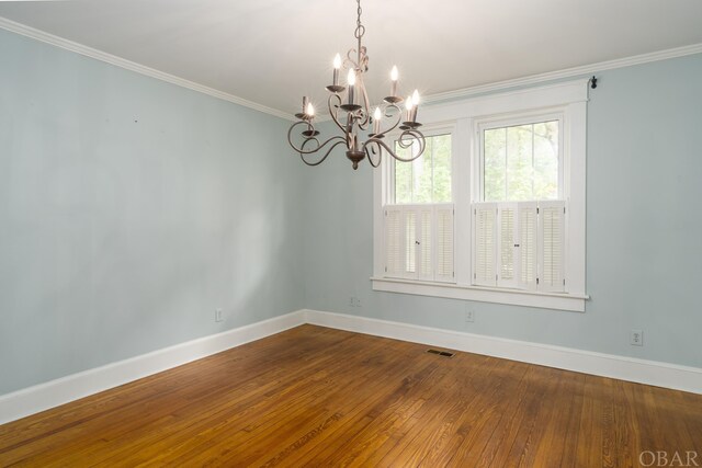 spare room featuring baseboards, wood finished floors, visible vents, and crown molding