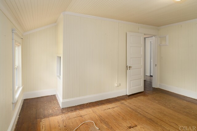 spare room featuring crown molding, baseboards, and wood finished floors