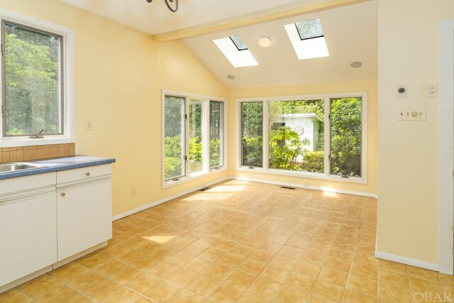 interior space with visible vents, vaulted ceiling with beams, baseboards, and light tile patterned flooring