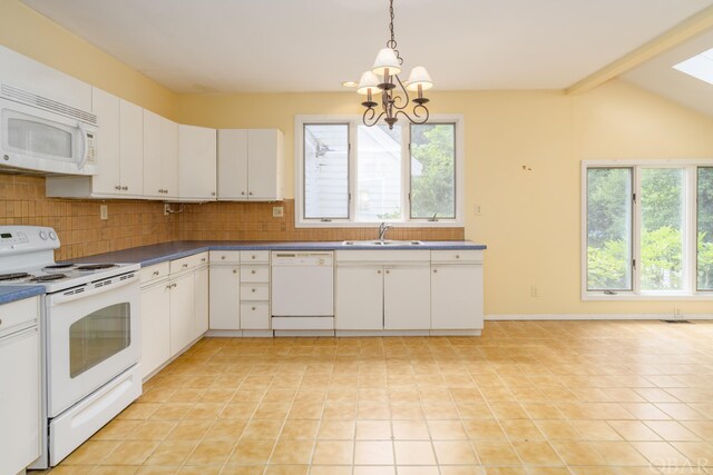 kitchen featuring white appliances, a sink, white cabinetry, hanging light fixtures, and dark countertops