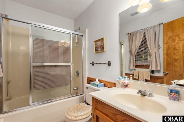 bathroom with a textured ceiling, enclosed tub / shower combo, toilet, visible vents, and vanity