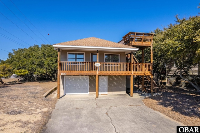 view of front of home with a shingled roof, concrete driveway, stairway, and a garage