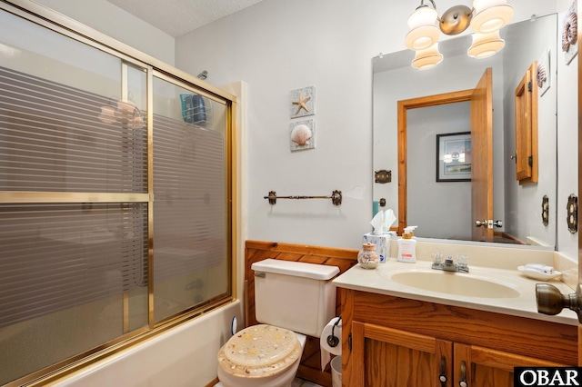 full bath featuring a wainscoted wall, toilet, vanity, and combined bath / shower with glass door