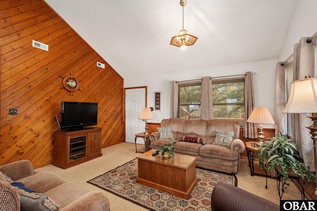 carpeted living room featuring lofted ceiling, visible vents, and wooden walls