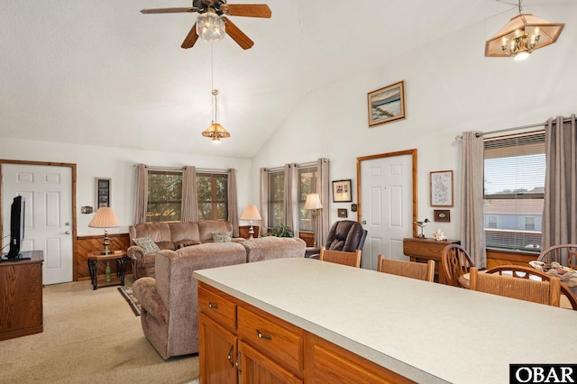 kitchen with light countertops, hanging light fixtures, brown cabinetry, open floor plan, and light carpet