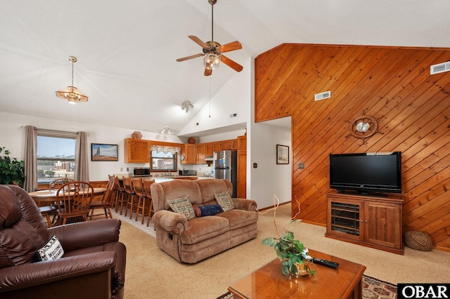 living room with light carpet, high vaulted ceiling, wood walls, and visible vents