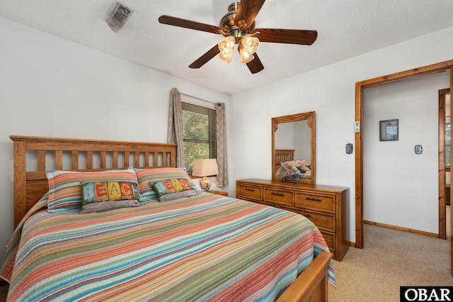 bedroom with ceiling fan, a textured ceiling, light carpet, visible vents, and baseboards