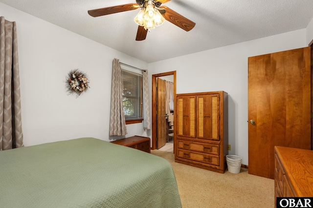 bedroom with light colored carpet, ceiling fan, and a textured ceiling