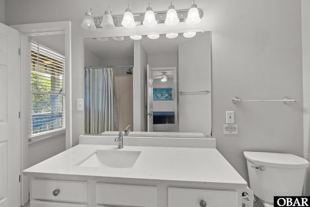 bathroom featuring toilet, curtained shower, vanity, and ceiling fan