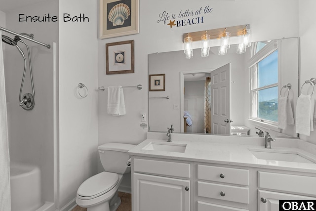 bathroom featuring toilet, double vanity, a sink, and walk in shower