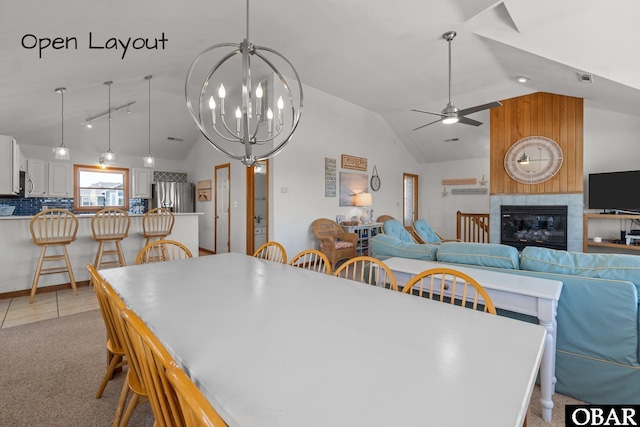 dining space with ceiling fan with notable chandelier, light carpet, a fireplace, and lofted ceiling
