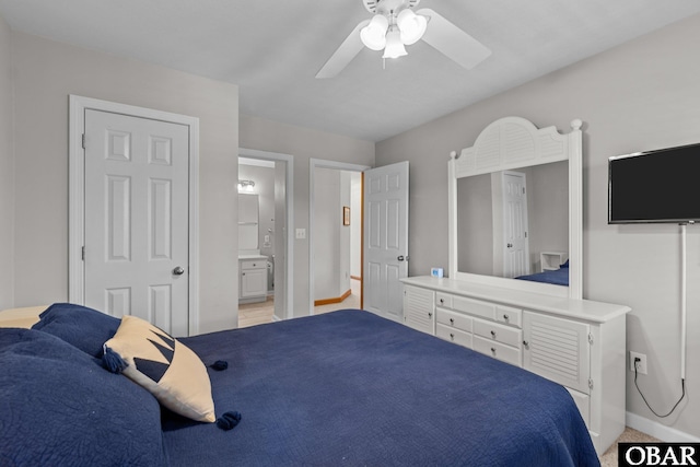 bedroom featuring ensuite bath, baseboards, and ceiling fan
