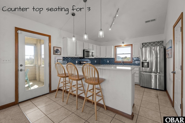 kitchen with tasteful backsplash, a peninsula, white cabinetry, visible vents, and appliances with stainless steel finishes