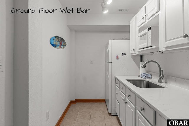kitchen featuring white microwave, visible vents, a sink, and white cabinets