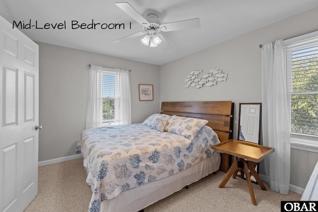bedroom featuring a ceiling fan, light carpet, baseboards, and multiple windows
