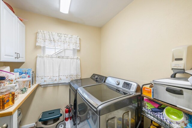 clothes washing area featuring independent washer and dryer and cabinet space