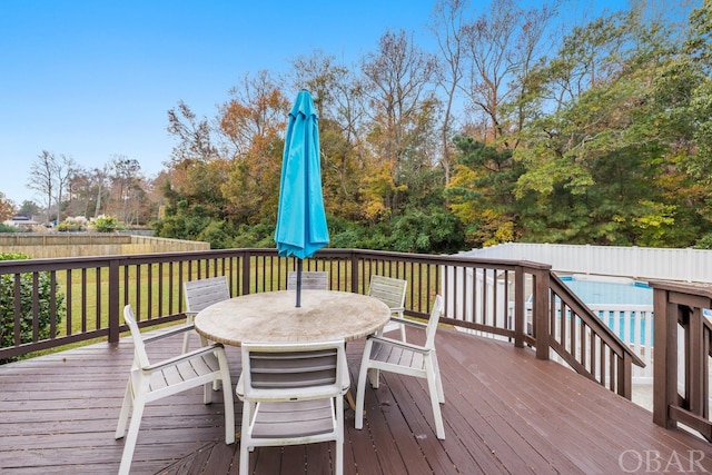 wooden terrace with outdoor dining area and a fenced backyard