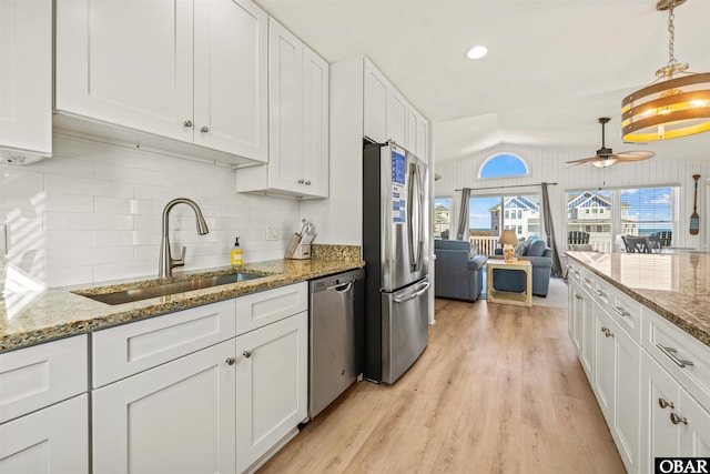 kitchen featuring lofted ceiling, stainless steel appliances, a sink, white cabinets, and light wood-type flooring