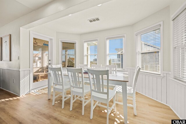 dining space featuring a wainscoted wall, light wood-style flooring, and visible vents