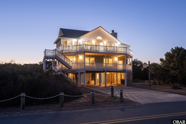 view of front of property with concrete driveway, fence, and stairs