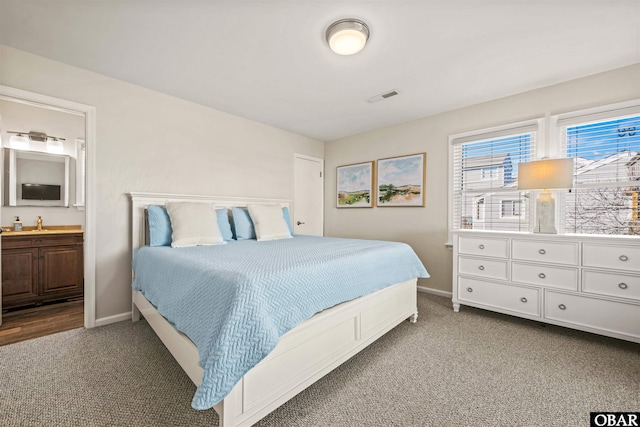 bedroom featuring carpet floors, visible vents, ensuite bath, and baseboards