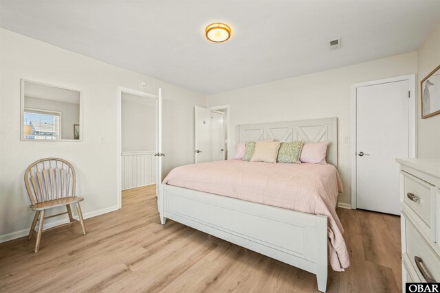 bedroom featuring light wood-style flooring, visible vents, and baseboards