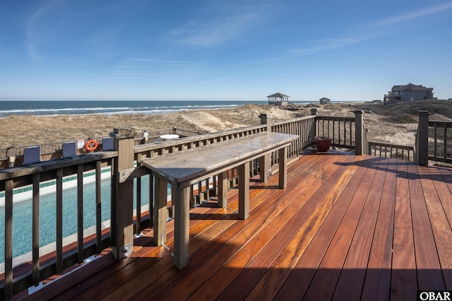 wooden deck featuring a water view and a beach view