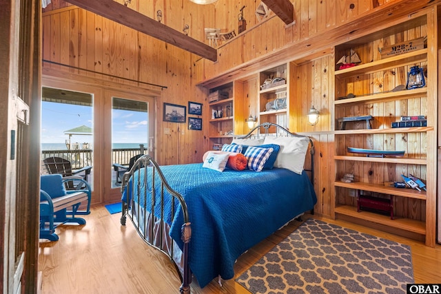 bedroom with access to outside, wood finished floors, and wooden walls