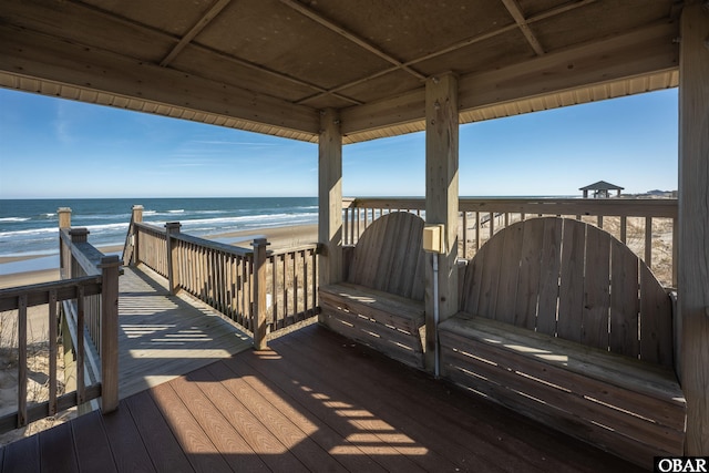 deck with a view of the beach, a gate, and a water view