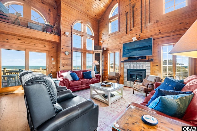 living room with a healthy amount of sunlight, a water view, wood walls, and light wood finished floors