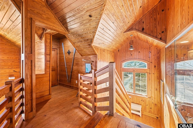 corridor featuring lofted ceiling, wood ceiling, wood finished floors, an upstairs landing, and wood walls