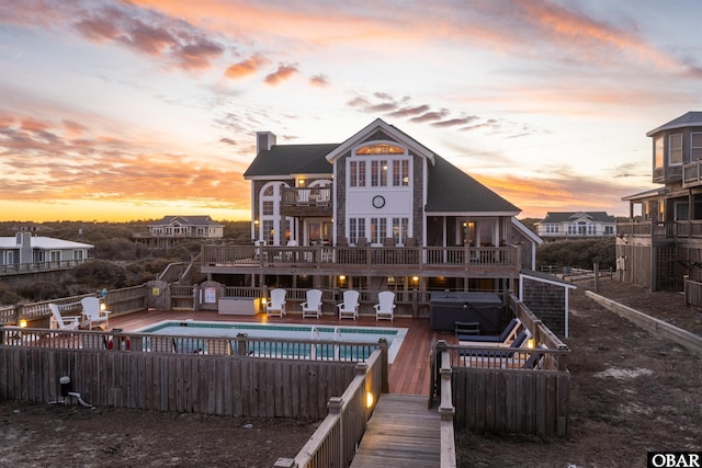 rear view of property with fence private yard, a balcony, a fenced in pool, a chimney, and a hot tub