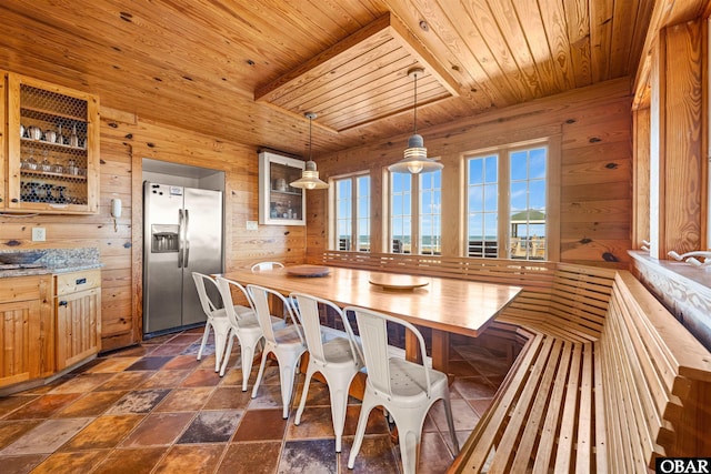 dining area with wooden ceiling, stone finish flooring, and wood walls