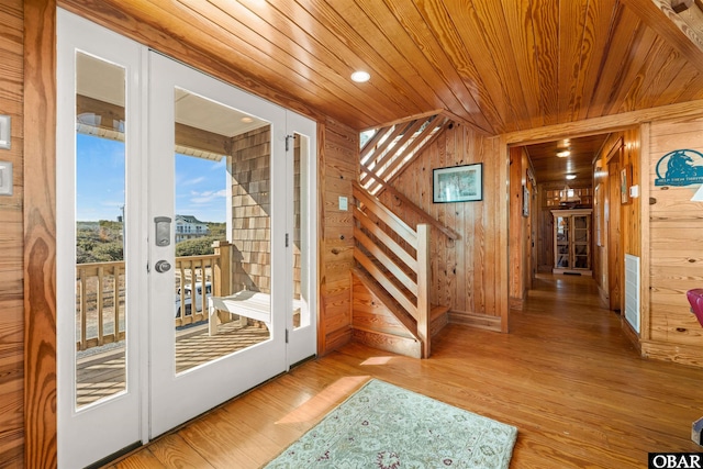 entryway featuring wooden ceiling, visible vents, light wood finished floors, and wood walls