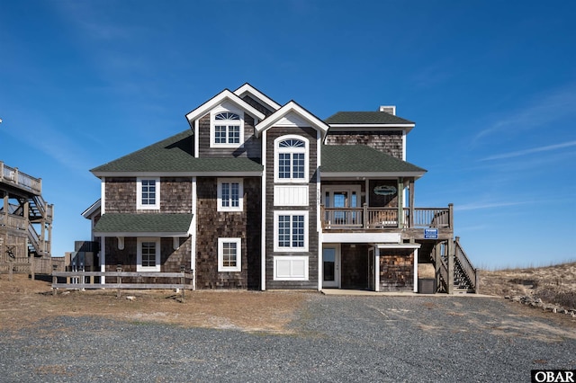 view of front of property featuring gravel driveway, a garage, and roof with shingles