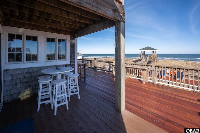 deck featuring a water view, exterior bar, and a view of the beach