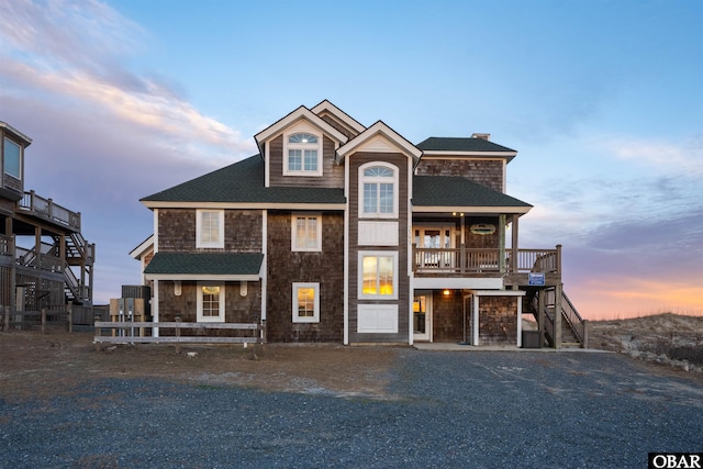 view of front of house with driveway, stairs, and roof with shingles