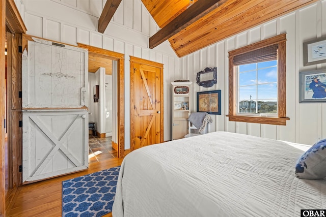 bedroom with vaulted ceiling with beams, wood finished floors, wood ceiling, and a decorative wall