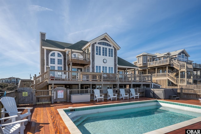 back of property featuring a hot tub, a chimney, a wooden deck, and a community pool